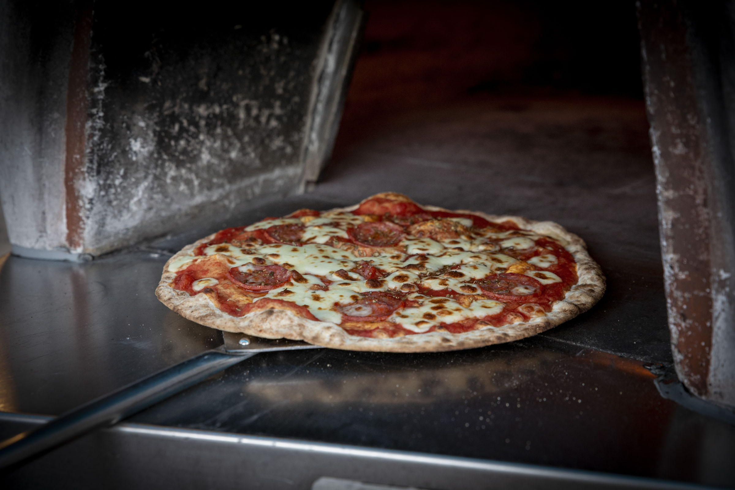 Neapolitan-style pizza cooking in wood-fired oven at corporate event in the West Midlands